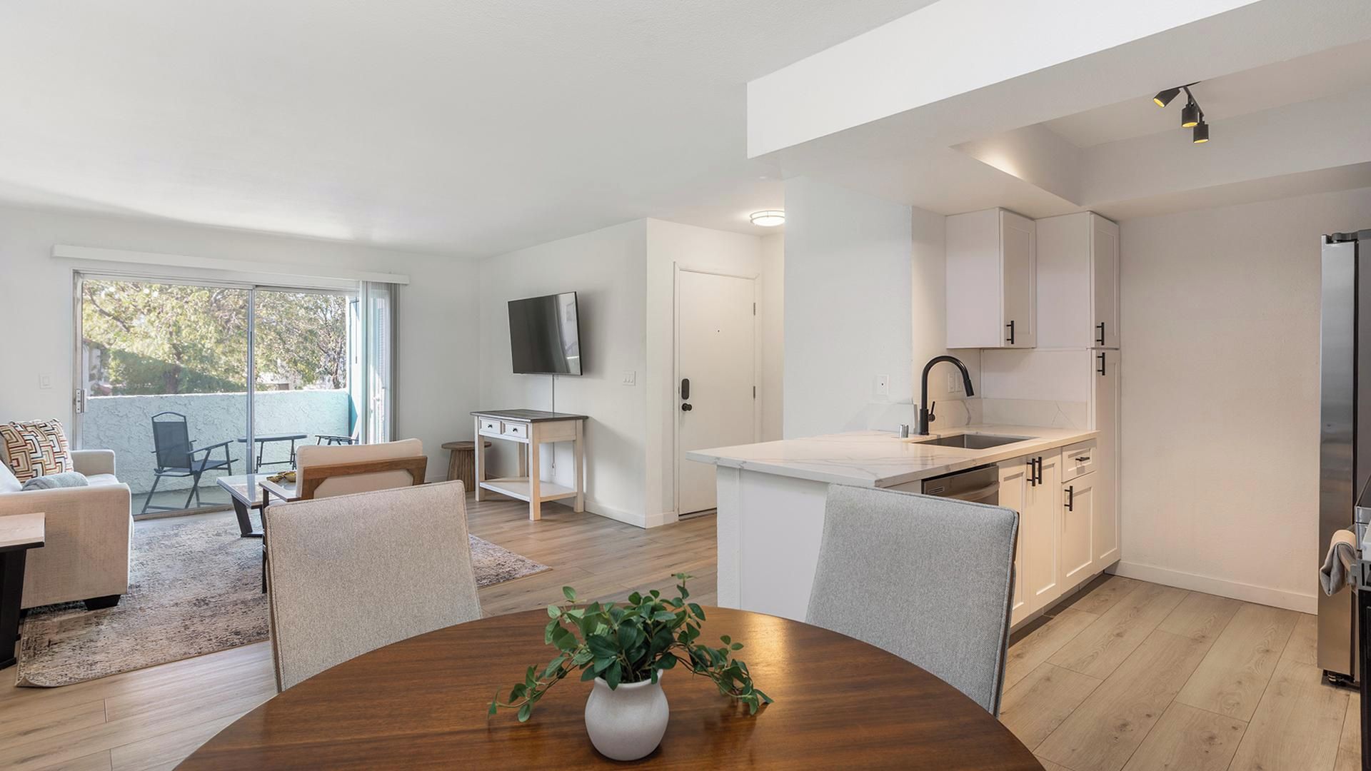 Un appartement moderne comprenant un coin repas, une cuisine et un balcon aménagé avec du mobilier d’extérieur.