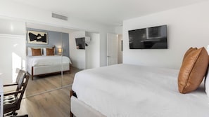 Een moderne hotelkamer met een groot bed, een bureau, een stoel, een flatscreen-televisie en een kledingkast met spiegel.