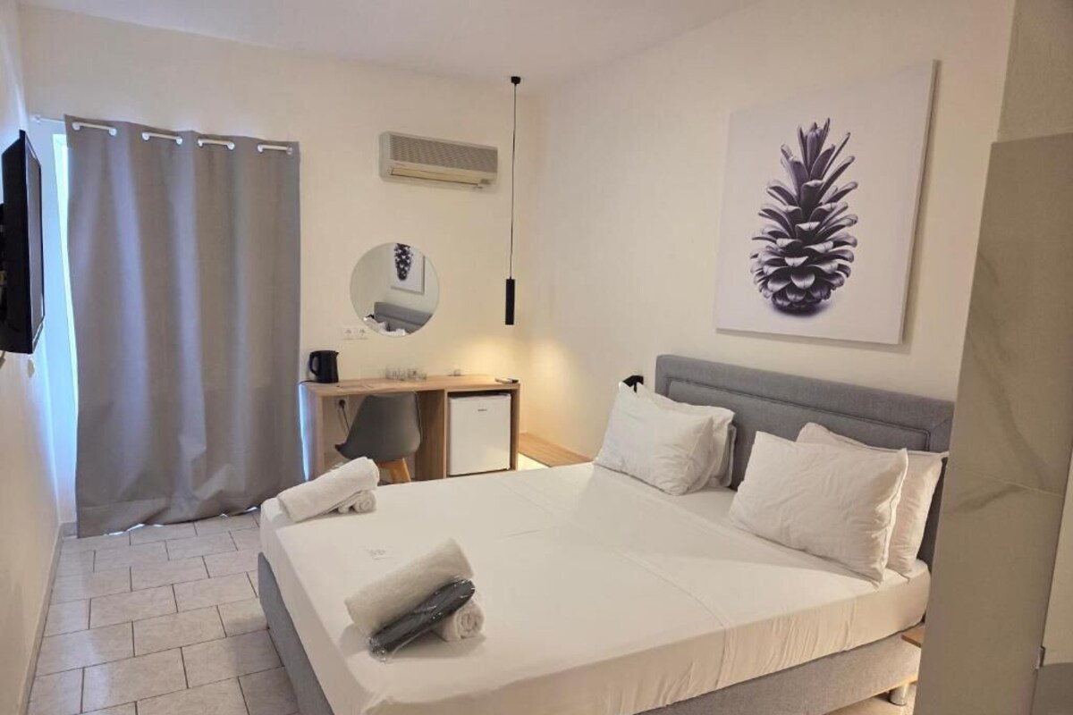 A bedroom with a bed, a desk, a chair, a mirror, and a pinecone artwork on the wall.