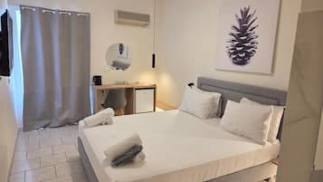 A bedroom with a bed, a desk, a chair, a mirror, and a pinecone artwork on the wall.