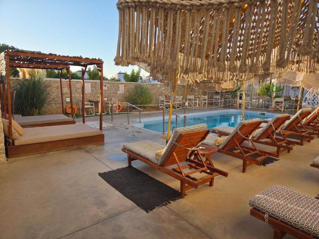 A poolside area with lounge chairs, a wooden pergola, and a rope canopy.