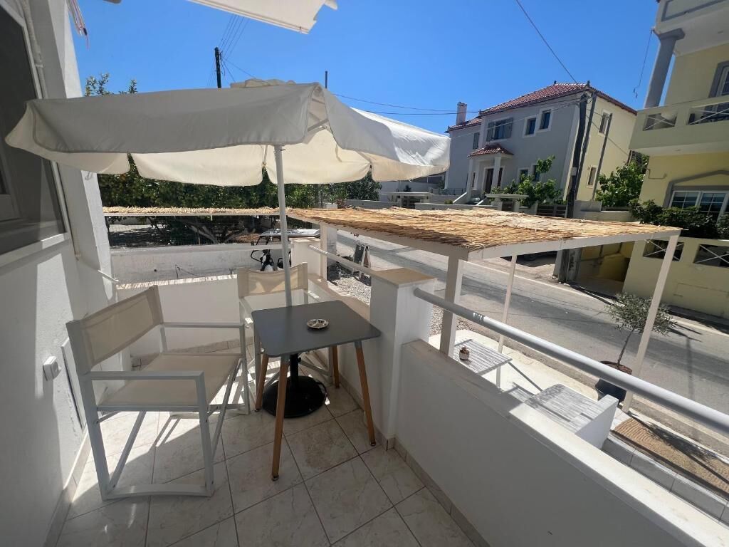 Ein Balkon mit Tisch, Stuhl und Sonnenschirm.