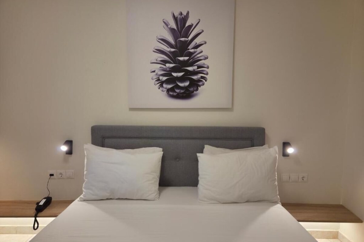 A bedroom with a bed, two bedside lamps, a headboard, and a wall-mounted artwork.