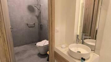 Et badeværelse med brusebad, toilet og håndvask.