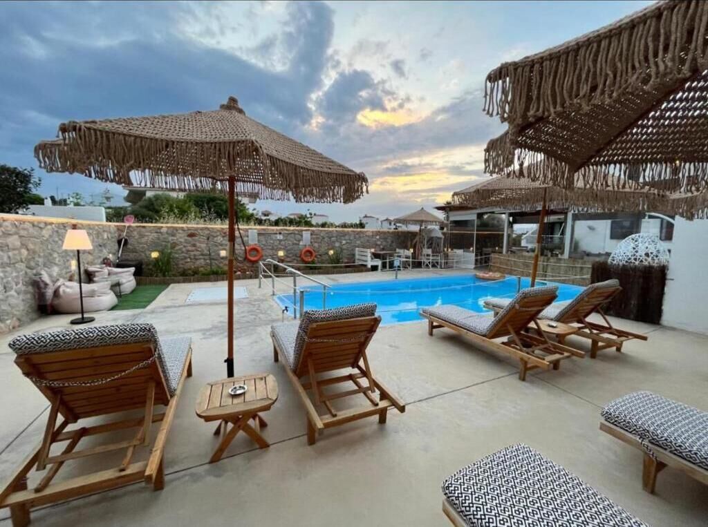 A poolside area with lounge chairs, umbrellas, and a stone wall.