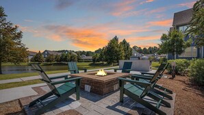 Une terrasse avec un foyer extérieur, des sièges et une vue sur un lac et des maisons.