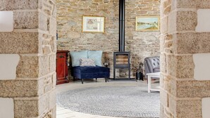 A stone-walled room with a fireplace, a sofa, and a rug. - Stunning Coastal Barn With hot tub (Falmouth)