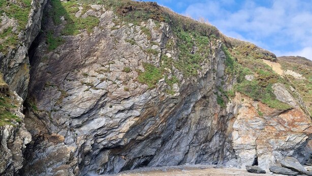 A coastal landscape with rocky cliffs, clear water, and a sandy beach. - Stunning Coastal Barn With hot tub (Falmouth)