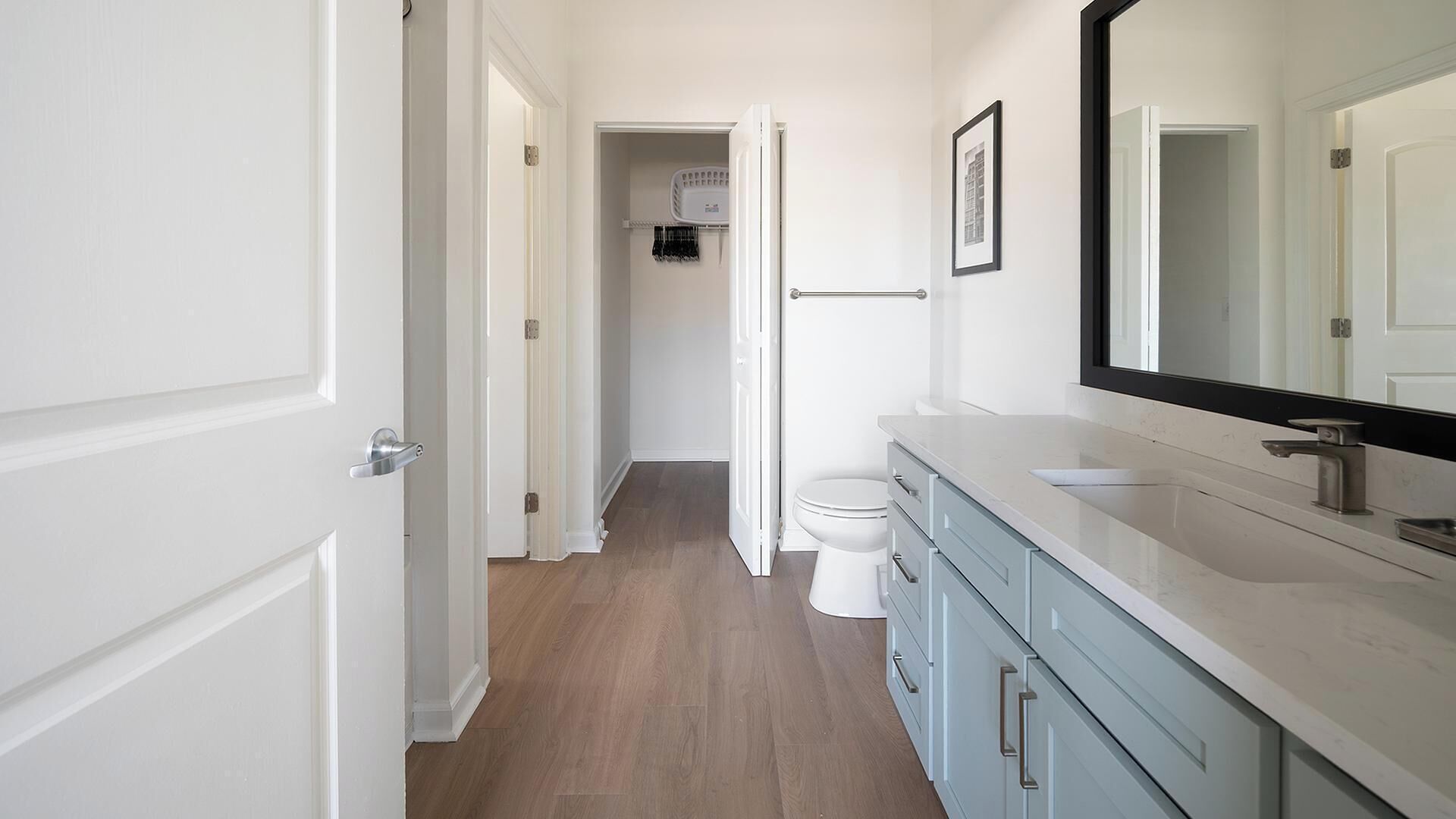 A bathroom with a white toilet, a sink with a large mirror, and a cabinet with drawers.