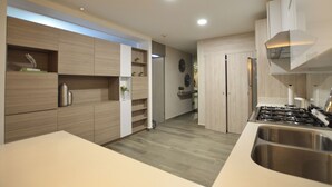 Une cuisine moderne dotée de meubles de rangement intégrés, d’un évier en acier inoxydable et d’une cuisinière à gaz.