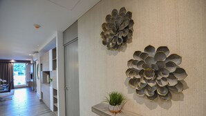 Un couloir doté d’un plancher en bois, une plante en pot posée sur une étagère et deux éléments décoratifs fixés au mur.
