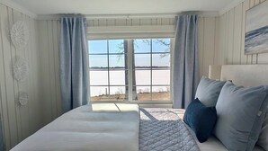 A bedroom with a bed, a window with curtains, a ceiling light, and a painting on the wall. - Lakefront Escape - Breathtaking Views in Fox Lake (Fox Lake)