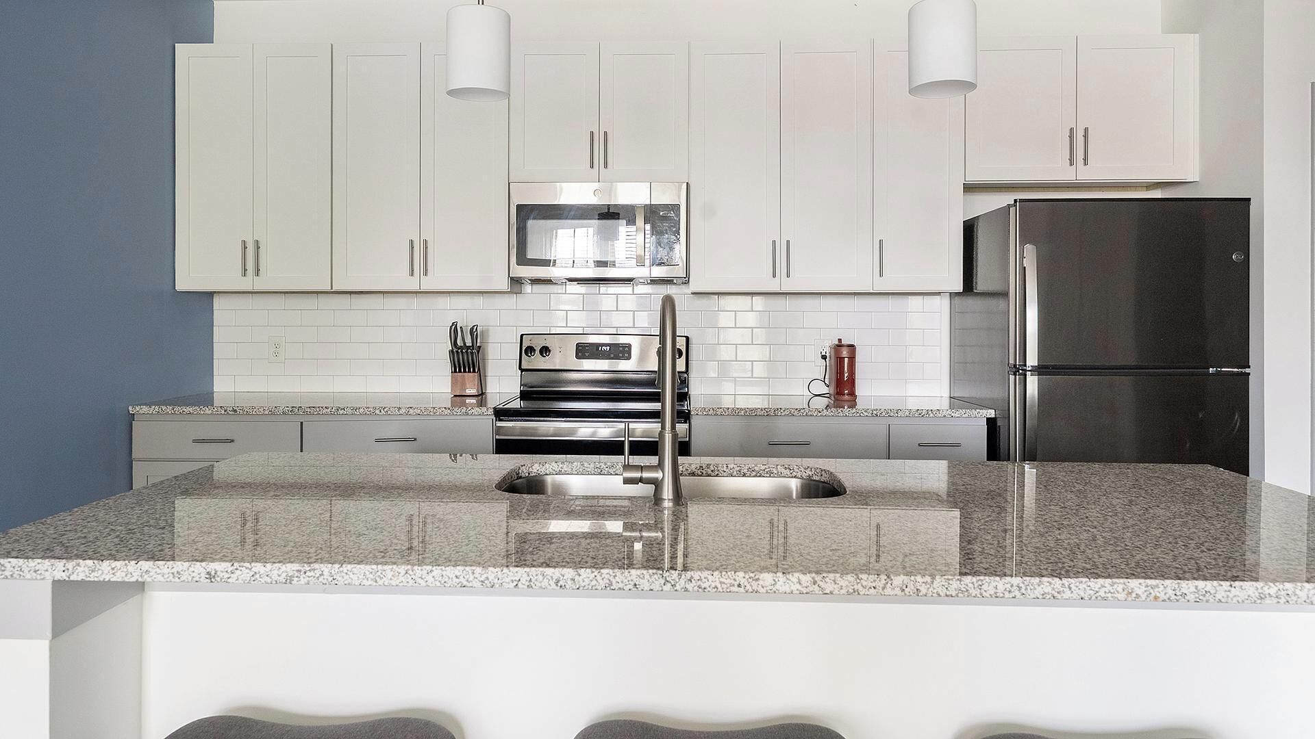 A modern kitchen with white cabinets, stainless steel appliances, and a granite countertop.