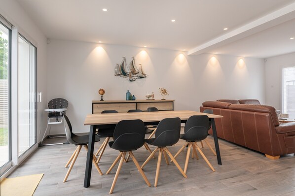 Un comedor moderno con una mesa de madera y sillas negras, un sofá de cuero marrón y una decoración de velero colgado en la pared.