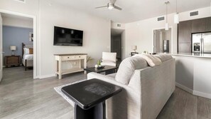 Ein modernes Wohnzimmer mit einer Couch, einem Couchtisch, einem Fernseher und einem Essbereich mit Tisch und Stühlen.