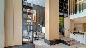 A modern interior with a staircase, a seating area, and a kitchen visible in the background. - Landing | Beautiful 1BD, Gym, Clubhouse (Fort Myers)