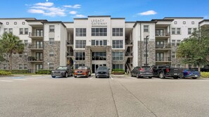 Un edificio de varios pisos llamado 'Legacy Gateway Apartments' con un estacionamiento al frente.