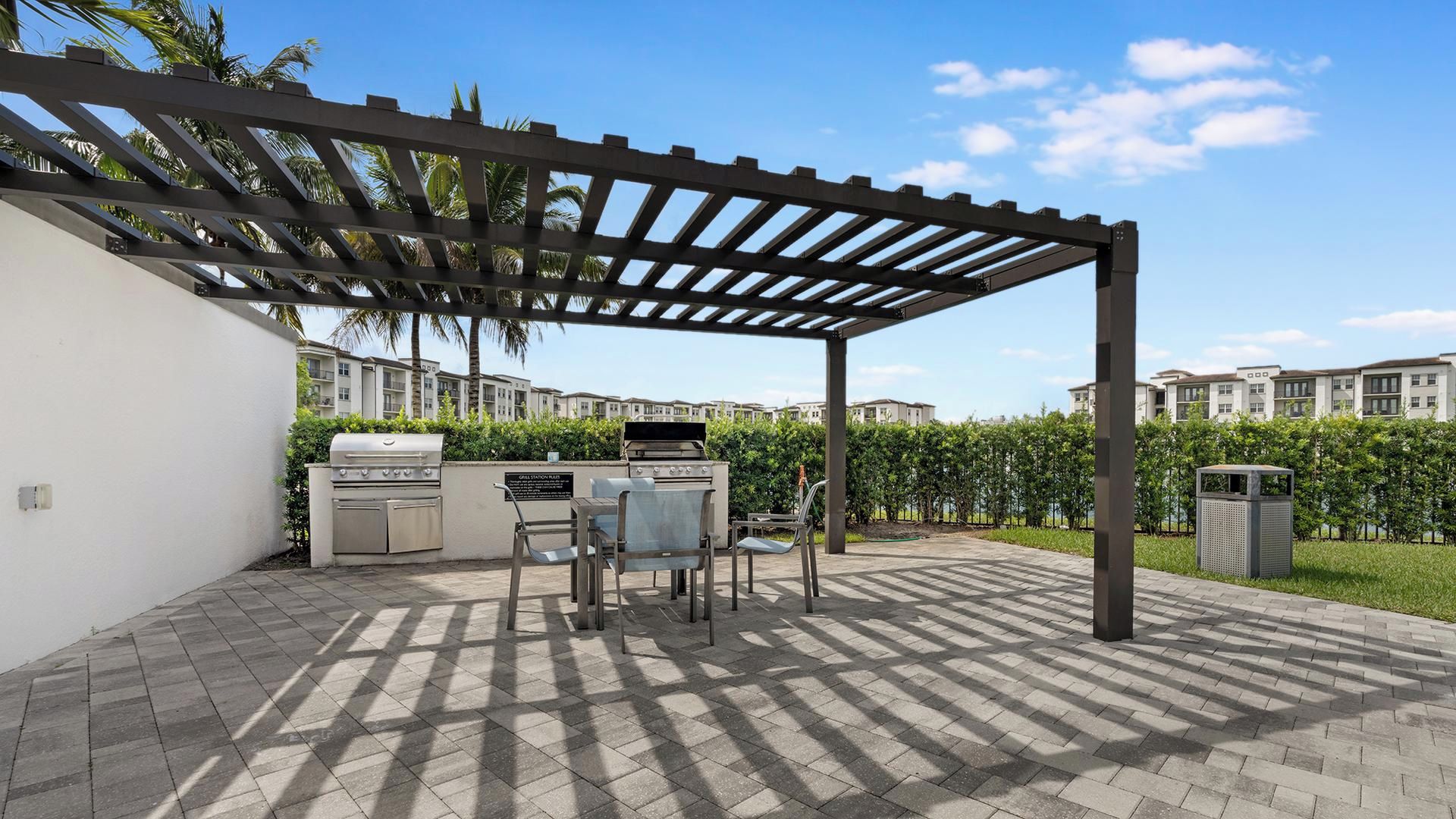 Patio esterno con barbecue, sedie e tettoia.