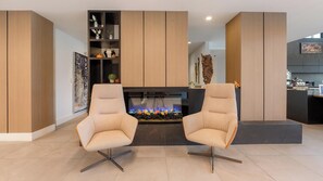 A modern living room with two armchairs, a fireplace, and a coffee bar in the background. - Landing | Beautiful 1BD, Gym, Clubhouse (Fort Myers)