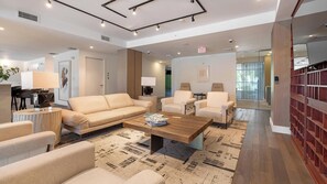 Un hall d’hôtel moderne avec un canapé, des fauteuils, une table basse et une bibliothèque.