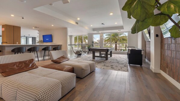 A spacious living area with a pool table, comfortable seating, and a view of the outdoors. - Landing | Incredible 2BD, Gym, Clubhouse (Fort Myers)