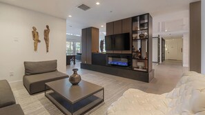 A modern living room with a sofa, a coffee table, a fireplace, and a TV. - Landing | Incredible 2BD, Gym, Clubhouse (Fort Myers)