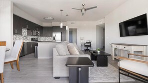 A modern kitchen with dark cabinets, a central island, and a dining area with a sofa and table. - Landing | Modern 2BD, Clubhouse, Gym (Fort Myers)