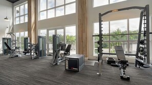 A gym with various exercise equipment, large windows, and a view of greenery outside. - Landing | Modern 2BD, Clubhouse, Gym (Fort Myers)