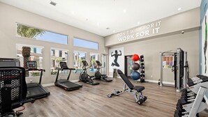 Ein Fitnessraum mit Laufbändern, Crosstrainern, einer Hantelbank und einem Squat-Gestell.