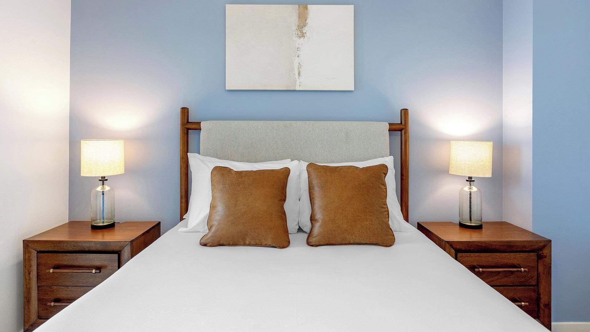 A hotel room with a large bed, two bedside tables, and two lamps.