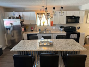 A modern kitchen with a central island, stainless steel appliances, and pendant lighting. - The Galley at Rathbun Lake Iowa (Monroe County)