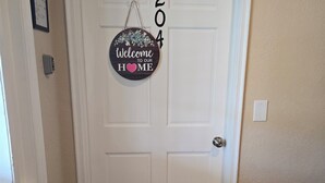 A white door with a 'Welcome to our home' sign and the number '204' above it.