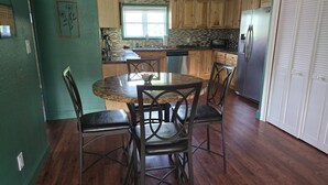 A kitchen with wooden cabinets, a dining table with chairs, and a refrigerator.