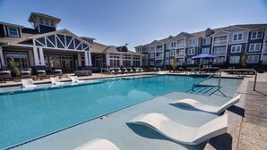 A swimming pool with lounge chairs and a building with balconies in the background. - Landing | Beautiful 1BD, Clubhouse, Yoga Studio (Murfreesboro)