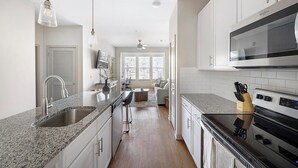A modern kitchen with granite countertops, stainless steel appliances, and a central island. - Landing | Modern 1BD, Gym, Yoga Studio (Murfreesboro)