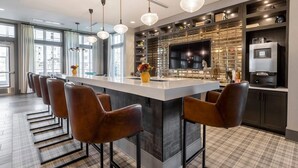 Cocina moderna con una isla central, taburetes de bar, un televisor grande y estantes empotrados.