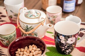 A collection of tea sets and cups on a table with a patterned tablecloth. - Luxury Apartment with Frescoes Rome Termini Colosseum (Roma)