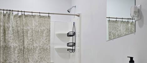 A bathroom with a toilet, shower, sink, and mirror.