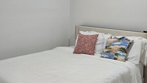 A bedroom with a bed, pillows, a headboard, and two wall art pieces. - 2-bedroom building in charming Stockbridge with cool AC (Stockbridge)