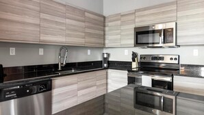 Eine moderne Küche mit Holzvertäfelung, Edelstahlgeräten, einer schwarzen Arbeitsplatte und einem eingebauten Backofen.