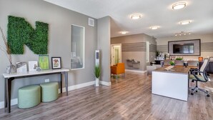 A modern interior with a reception desk, seating area, and a large flat-screen TV mounted on the wall. - Landing | Chic 1BD, Gym, Yoga Studio (Clearwater)