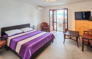 A hotel room with a bed, a desk, a chair, a television, and a balcony. - 2 bedroom gorgeous apartment in Slatine (Slatine)