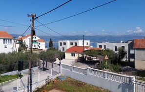 A residential area with white buildings, a white fence, and a view of the sea and mountains in the background. - 2 bedroom gorgeous apartment in Slatine (Slatine)