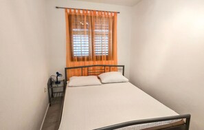 A small, single-bed room with a window, a bedside table, and a lamp. - 2 bedroom gorgeous apartment in Slatine (Slatine)