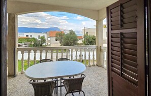 A balcony with a table and chairs, overlooking a street with buildings and mountains in the distance. - Amazing apartment in Slatine with WiFi (Slatine)