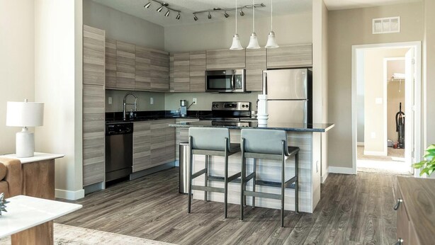 A modern kitchen with a central island, stainless steel appliances, and a bar seating area. - Landing | Stunning 1BD, Pool, Gym (Clearwater)