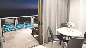 A balcony with a pool view, a round table with chairs, and a sliding glass door. - Luxury, Family-Friendly Studio 1-0802A on the Beach! (Puerto Peñasco)