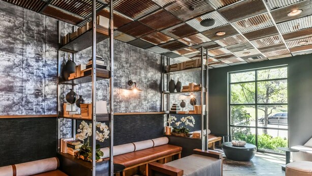 A modern interior with a high ceiling, metal beams, and a large window offering a view of the outdoors. - Landing | Incredible 1BD, Clubhouse, Gym (Lewisville)