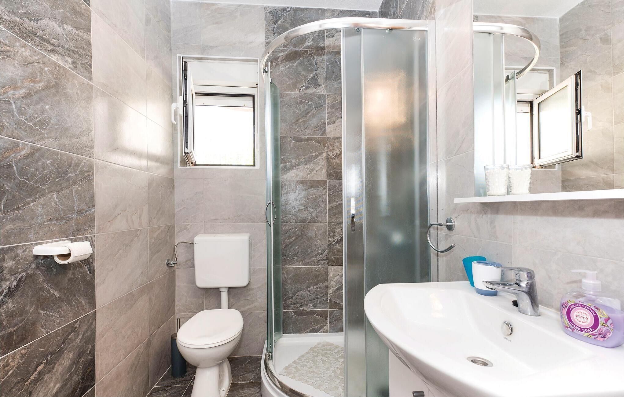 A bathroom with a shower, toilet, and sink.