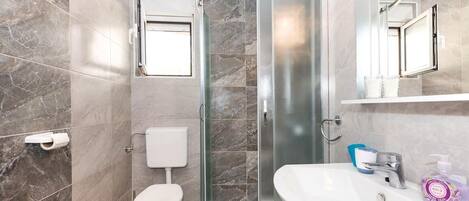 A bathroom with a shower, toilet, and sink.